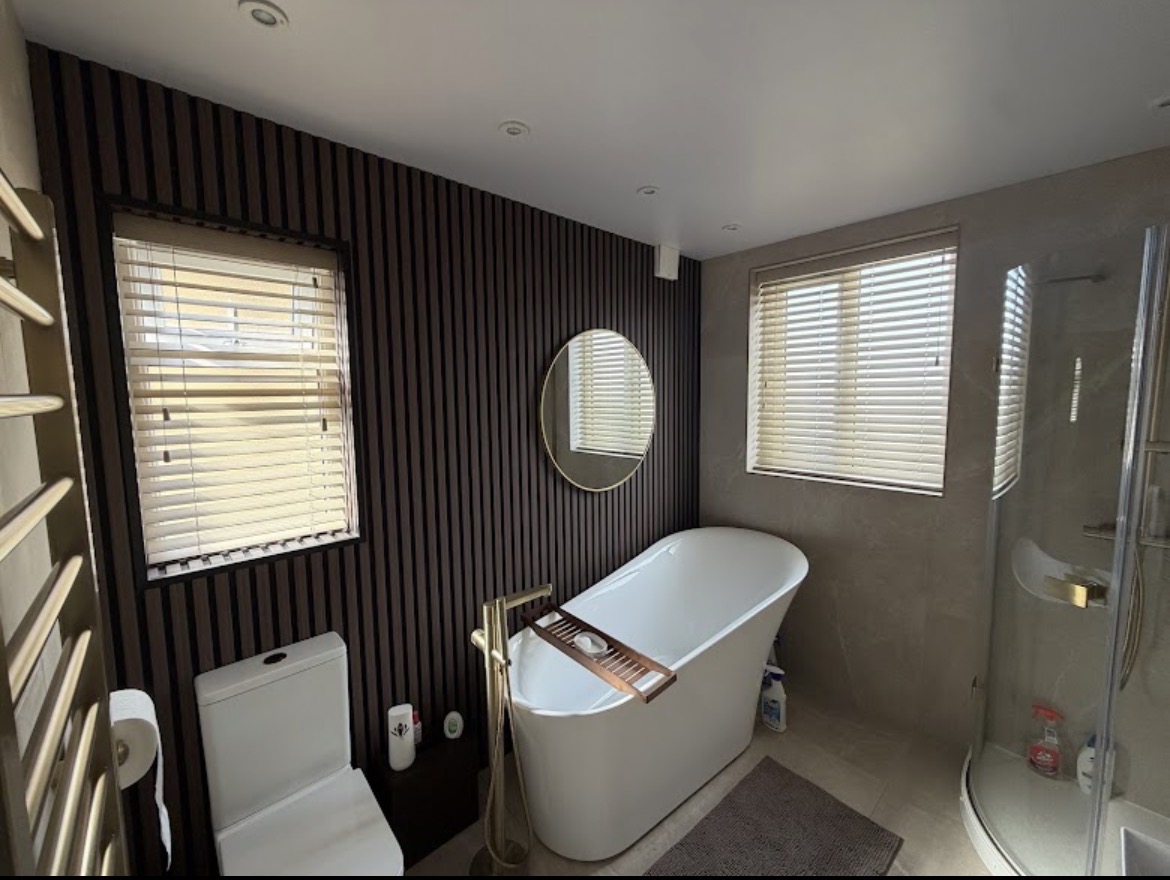 Cream wooden blinds in a panelled bathroom